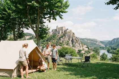Famille installant une tente dans un camping à Sisteron avec la citadelle médiévale en arrière-plan